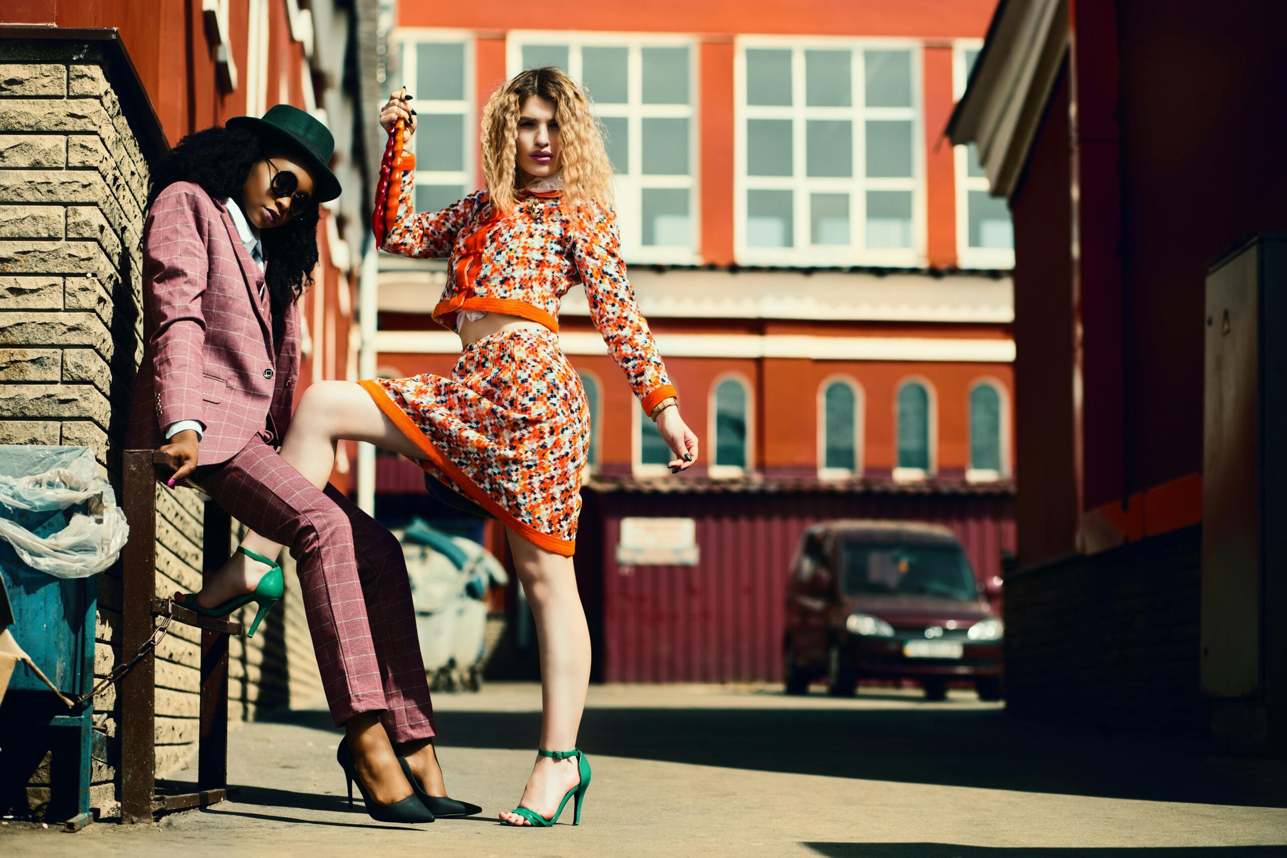 Collections Stylish women posing in an urban alley showcasing contemporary fashion trends.